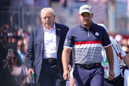 Bryson DeChambeau camina junto al presidente Donald Trump en la primera jornada de la competencia por la Copa Ryder, en Nueva York; Estados Unidos necesita reponerse ante Europa.