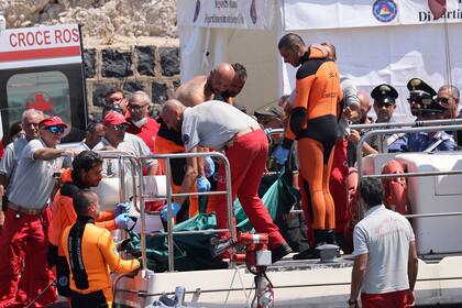 Buzos del departamento de bomberos de Italia desembarcan una bolsa de plástico con el cuerpo de una de las víctimas de un naufragio, en Porticello, Sicilia, en el sur de Italia, el viernes 23 de agosto de 2024. (Alberto Lo Bianco/LaPresse vía AP)