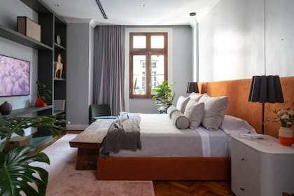 Cama con respaldo entelado y mesas de luz (todo de Urbano Estudio). Florero (Familia DDD), lámpara colgante ‘Renata 32’ (Iluminación Agüero) y jarrones (Mamá Elefanta).