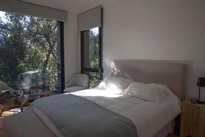 Cama con respaldo tapizado, sillones y cortinas al tono.