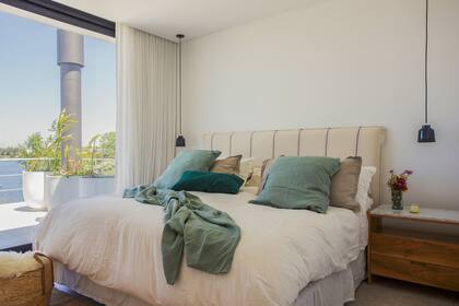 Cama con textiles de Niki Home Deco y respaldo con funda para un lavado fácil. Mesas de noche (Arq. Maura Ambrosetto) de petiribí con tapa de mármol Carrara. Lámparas de techo (Ambos Lighting).