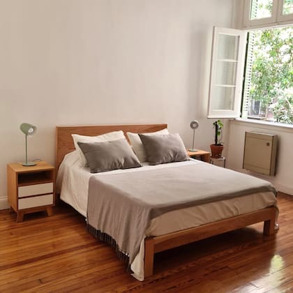 Cama de lineas simples, con cuatro patas, y la simpleza de las sábanas, una manta al pie y almohadas