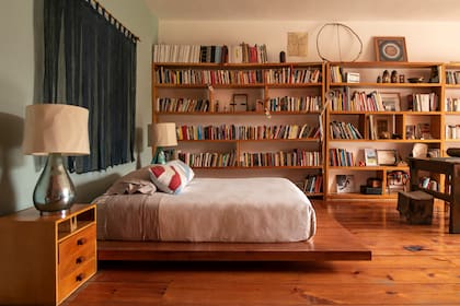 Cama sobre plancha de madera, biblioteca y escritorio para un cuarto de color envolvente.