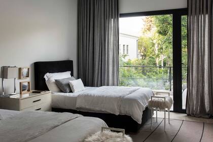 Camas tapizadas en terciopelo (Caro Deane) vestidas con acolchados de lino (Luchi Arrechea), mesa de luz (Duveen) y cortinas de lino con borde negro.