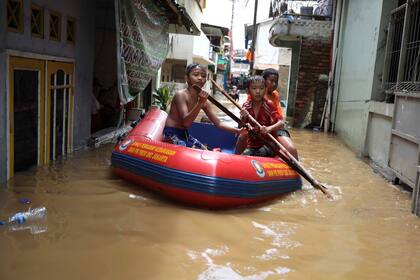 Un grupo de niños se mueve en bote por la calles de Yakarta