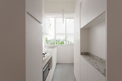 Cambio radical con una paleta predominantemente blanca que potencia la luz y la amplitud visual. Las plantas y la piedra natural en la mesada (Oscar Revestimientos) suman su dosis de calidez. Luminaria colgante (Lucciola).