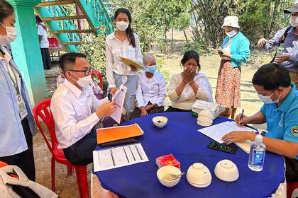 Esta imagen publicada por el Departamento de Control de Enfermedades Transmisibles de Camboya (CDCD) el 23 de febrero de 2023 muestra a los expertos del CDCD educando a los aldeanos sobre las amenazas del virus H5N1, en la provincia de Prey Veng