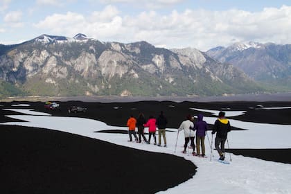 Caminata con raquetas en el Parque Nacional Conguillío, con nieves eternas que contrastan con el suelo negro