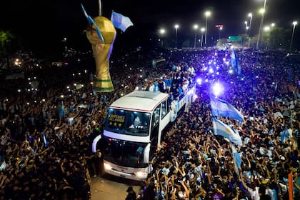 TOPSHOT - This aerial image taken on December 20, 2022 shows Argentina's players celebrating on board a bus with supporters after winning the Qatar 2022 World Cup tournament as they leave Ezeiza International Airport en route to the Argentine Football Association (AFA) training centre in Ezeiza, Buenos Aires province, Argentina. (Photo by Tomas CUESTA / AFP)