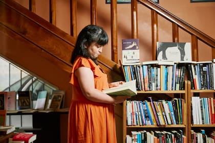 Cande revisa los estantes de la librería; en su tiempo libre, lee novelas de romance y misterio