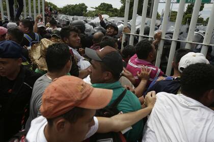 Cientos de migrantes que iban al frente de la caravana lograron cruzar los puestos fronterizos de Guatemala sobre el puente, pero fueron rechazados por decenas de policías mexicanos que usaron escudos para detenerlos