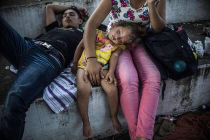 Migrantes hondureños descansan durante una parada en su viaje, en Huixtla