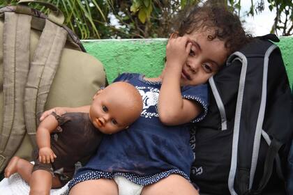 Una niña descansa junto a su muñeca en un alto de la caravana que se dirige a EE.UU.