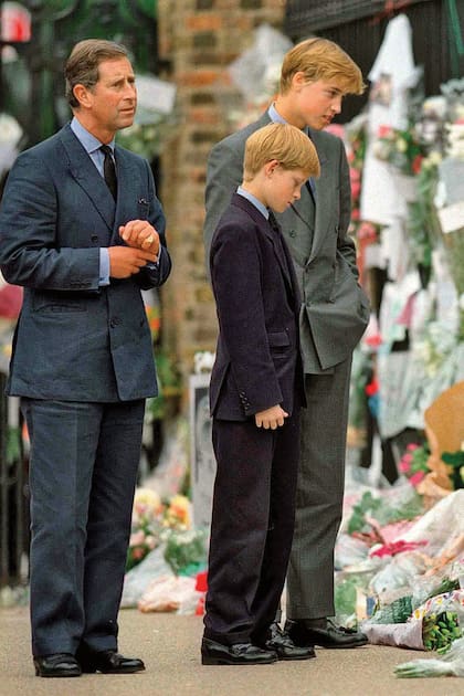 Carlos, entonces príncipe de Gales, y sus hijos William y Harry contemplan las flores que la gente dejó en las afueras del Palacio de Kensington como tributo a Lady Di, que murió el 31 de agosto de 1997.
