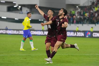 Carlos Faya (izquierda) y Matías Lacava, de la selección de Venezuela, festejan un autogol de Brasil en un partido del Preolímpico Sudamericano, el jueves 1 de febrero de 2024, en Caracas (AP Foto/Ariana Cubillos)
