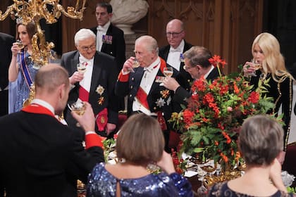 Carlos III y el presidente Steinmeier inician el brindis, al que se suma Claudia Schiffer. El menú del banquete consistió en trucha ahumada con langostinos, supremas de perdiz de Windsor y un postre de moras, vainilla y frambuesa. Para homenajear a los visitantes, se sirvió también un cóctel con sabor a chocolate y brandy de cereza, cuyas notas recordaban a la torta Selva Negra, originaria de Alemania