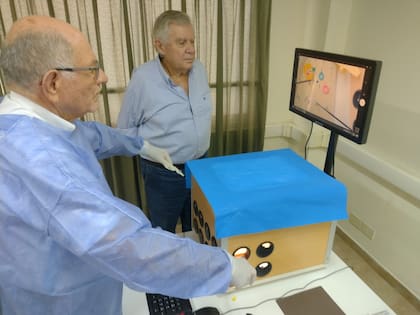 Carlos Spector, decano de la Facultad de Ciencias de la Salud, y Alfredo André, prosecretario de la UCES (centro), operan el simulador que diseñaron durante la pandemia de Covid-19