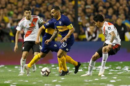 Carlos Tévez intenta pasar entre dos jugadores de River
