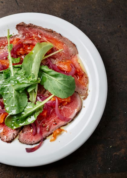 Carne wagyu asada y cortada bien fina con emulsión de mostaza, pickles de cebolla morada, tomate asado y rúcula fresca