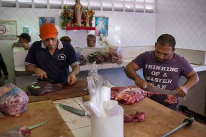 Carniceros cortan carne en un mercado de alimentos en Caracas, Venezuela, el 28 de enero.