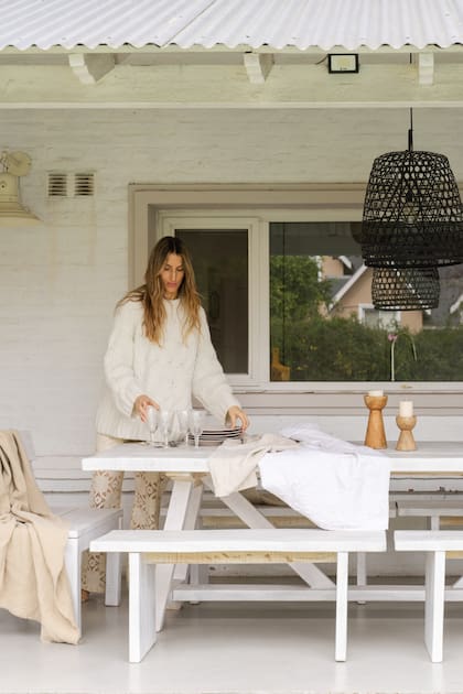 Carolina en la galería del jardín: juego de mesa y sillas blanco (Casa Paz), manta (Gloria Atelier Deco), candelabros de madera y mantel (Landmark). Lámparas galponeras (Design Lovers).