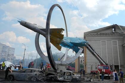 Cars destroyed by a deadly Russian missile attack stand near a monument in honor of the Ukrainian Air Force with a Soviet MiG-21 fighter jet in Vinnytsia, Ukraine, Thursday, July 14, 2022. (AP Photo/Efrem Lukatsky)
