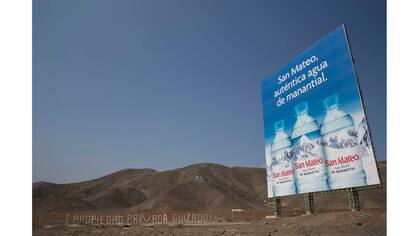Cartel que anuncia agua de manantial se encuentra a lo largo de la Carretera Panamericana en un área donde la gente vive en hogares sin agua potable