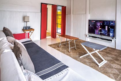 El cuarto de la televisión es la zona que más usan los hijos de Eugenio, Julio y Carmen, más allá de sus respectivos cuartos.Las puertas plegables en rojo vivo, como la de la entrada, suman carácter al ambiente.