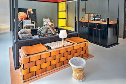 El fuego central del living-comedor-bar funciona como un fogón interior. Delante de él, un mueble creado por el dueño de casa para guardar la leña en hierro y cuero, que hace las veces de asiento y mesa de apoyo.