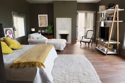 La suite principal tiene una chimenea con frente de mármol, una chaise longue y una silla de estilo francés que componen una suerte de living íntimo. Está pintada de gris, que destaca los textiles y las obras de arte (al fondo, sobre el escritorio, un cuadro de Juan Carlos López).