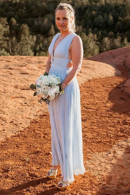 Cat lució un vestido íntegramente
drapeado, de escote profundo, en
color celeste claro, que acompañó
con sandalias con plataforma y taco cuadrado en blanco, al igual que su ramo de novia