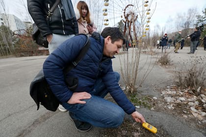 Un turista mide los niveles de radiación todavía presente entre los restos del pueblo