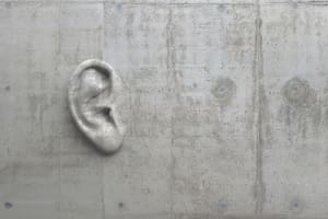 Cement sculpture in the shape of a human ear on a concrete wall. Illustration of the metaphor "Even walls have ears." Creative conceptual modern art with copy space. 3D rendering