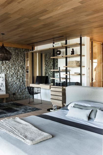 Cerca de la cama, el escritorio (Arquimadera) se apoyó junto a un nuevo muro de piedra, en un rincón que reitera los colores predominantes: blanco, negro, gris, beige. Cielo raso en madera (Patagonia Flooring)