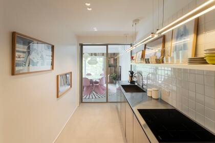 Cerrada pero a la vez expuesta, la cocina está comunicada por una doble puerta vidriada. Revestimiento de azulejos de 10x10 con juntas blancas.