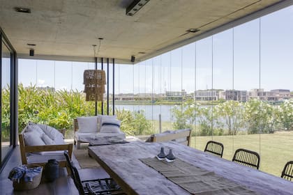 Cerramiento de vidrio y sillones de petiribí (Estudio Gambotto). Mesa ratona de quebracho recuperado (Guazu Nambi). Lámpara colgante de ratán (Puerto de Frutos).