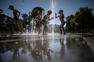 Chicos se refrescan en una fuente en Nantes. (Photo by Loic VENANCE / AFP)