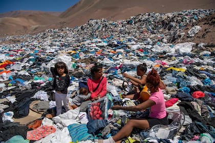 Varias mujeres revuelven la montaña de ropa desechada
