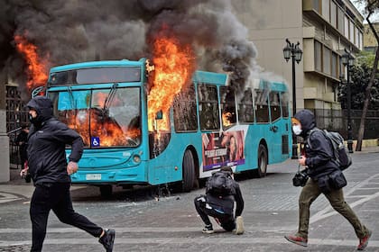 En esta foto de archivo tomada el 27 de mayo de 2022, un autobús arde en llamas después de ser alcanzado por una bomba incendiaria lanzada durante una marcha estudiantil para exigir al gobierno mejoras en el sistema educativo en Santiago.