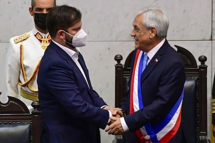 Sebastian Piñera saluda a Gabriel Boric al entregarle la banda presidencial, el 11 de marzo de 2022, en Valparaíso. (MARTIN BERNETTI / AFP)