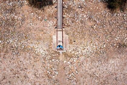 Vista aérea de un hombre observando desde un muelle el embalse seco de Collahue, en El Melón, Chile
