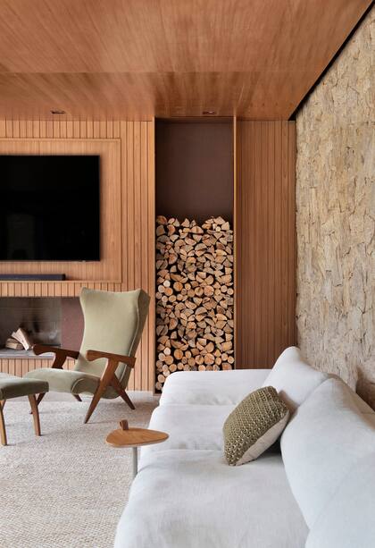 Chimenea y leñero en acero corten. Poltrona 'Cuca', diseño del brasileño Zanine Caldas, tapizada en terciopelo verde.