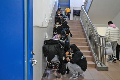 Unos niños reciben un goteo en las escaleras de un hospital infantil de Pekín el 23 de noviembre de 2023. 