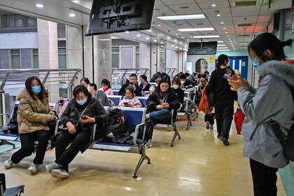 Niños y sus padres esperan en una zona de consultas externas de un hospital infantil de Pekín el 23 de noviembre de 2023.