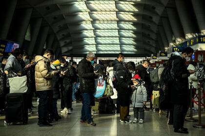 Una fila de turistas chinos en una estación de trenes en Pekín