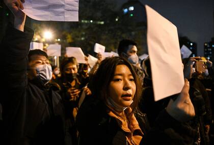 Manifestantes marchan a lo largo de una calle durante una concentración en favor de las víctimas de un incendio mortal, así como una protesta contra las duras restricciones Covid-19 de China, en Pekín, el 28 de noviembre de 2022.