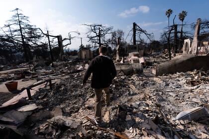 Chris Wilson camina el jueves 30 de enero de 2025 sobre los restos de su casa, que fue consumida por el incendio Eaton, en Altadena, California