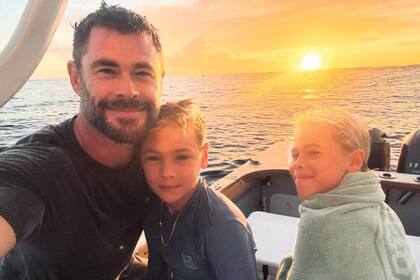 Chris y sus hijos Sasha y Tristan posan con un atardecer de lujo sobre el mar.