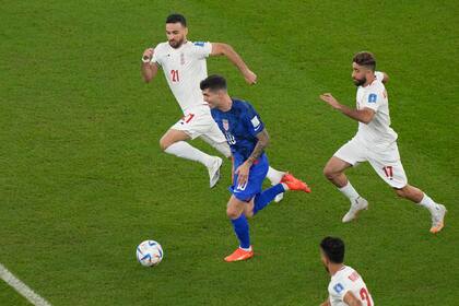 Christian Pulisic conduce perseguido por los iraníes Ahmad Nourollahi y Ali Gholizadeh, en un partido decisivo por el Grupo B.