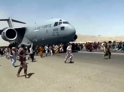 Cientos de personas desesperadas por escapar de Afganistán corren junto a un avión de la Fuerza Aérea de Estados Unidos mientras se mueve en la pista del aeropuerto internacional de Kabul, el lunes 16 de agosto de 2021.